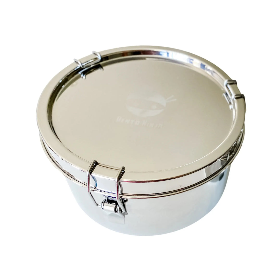 Large round stainless steel leakproof lunchbox by Bento Ninja with three spring hinged clasps holding the lid tightly in place.