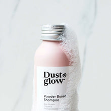 Dust & Glow powder-based shampoo in a pink recyclable aluminium bottle with suds and foam on one side. Vegan and made in New Zealand.