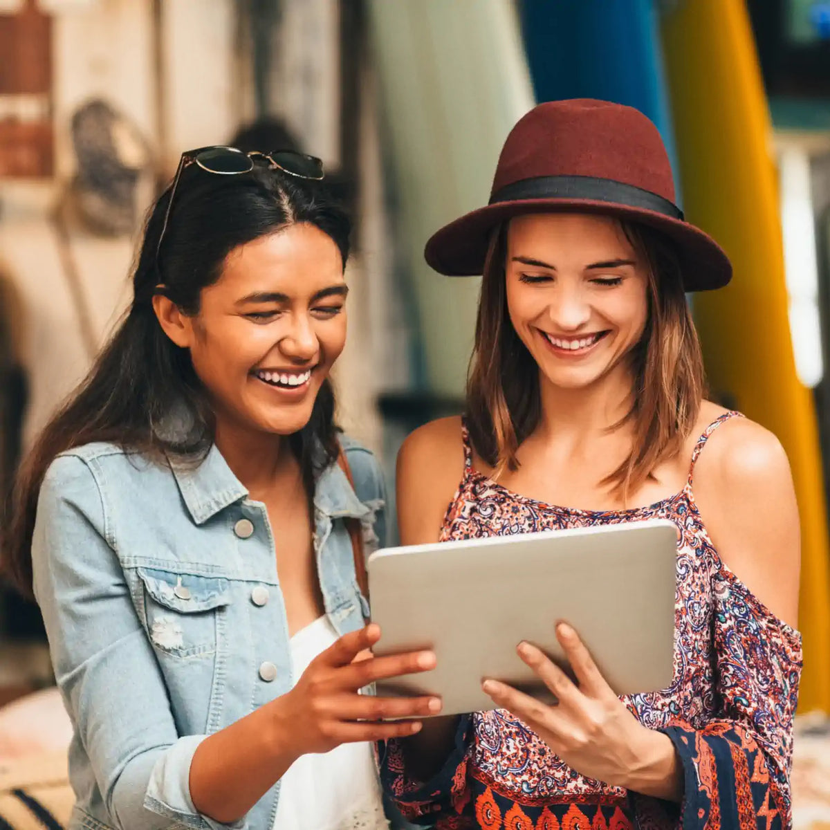 Image of two ladies smiling and laughing as they both look at a tablet screen to depict our Earthlove loyalty rewards programme.