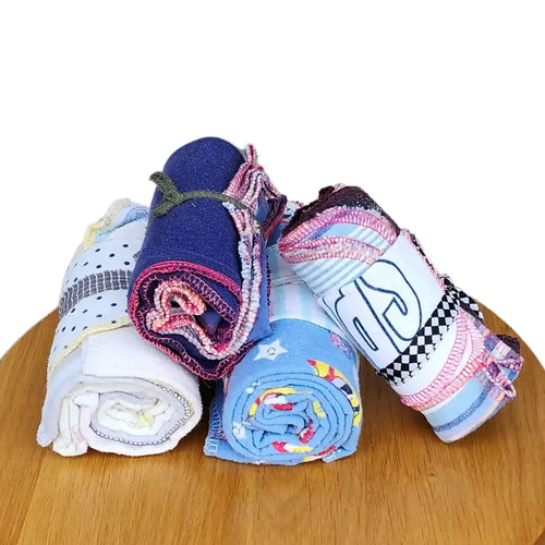 Glad rag recycled cotton cleaning cloths, bundles of colourful cloths piled on top of each other on a wooden board.