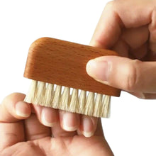 Natural wooden nail brush made from white boar bristles and beechwood being used to scrub fingernails.