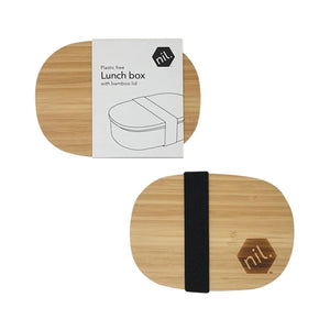 Top down vie of two of the nil stainless steel lunchbox. Only the bamboo lid and the wide black fabric strip of the elastic band holding the lid in place can be seen in this image along with the nil. logo which has been branded onto the wooden lid. The second lunchbox has a white paper card packaging sleeve around it, Sleek, stylish and minimal design.