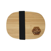 Top down vie of the nil stainless steel lunchbox. Only the bamboo lid and the wide black fabric strip of the elastic band holding the lid in place can be seen in this image along with the nil. logo which has been branded onto the wooden lid. Sleek, stylish and minimal design.