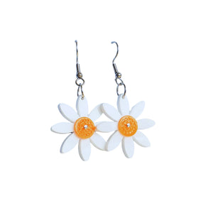Remix Plastic's Akaroa Daisy flower earrings made from salvaged acrylic offcuts and the orange flower head is made from yogurt container lids which would otherwise be going to landfill. Earrings have s tainless steel hook and are seen here hanging on a white background.