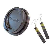 Raw materials: long black earrings with gold accents and a black single-use plastic coffee cup lid by Remix Plastic.