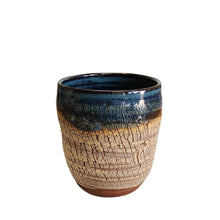 Ceramic drinking tumbler handmade by Wellhandled Ceramics with a rich dark red coloured clay, creamy crackled texture and a midnight blue glaze around the rim of the cup.