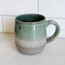 Ceramic coffee mug with handle handmade by Wellhandled Ceramics with a grey coloured clay and a white and light green glaze.