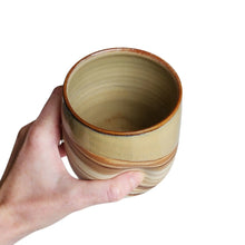 Extra large ceramic drinking tumbler handmade by Wellhandled Ceramics with a marbled clay and a light creamy coffee coloured glaze. Pictured with a hand holding the tumbler emphasising the thumb dent.