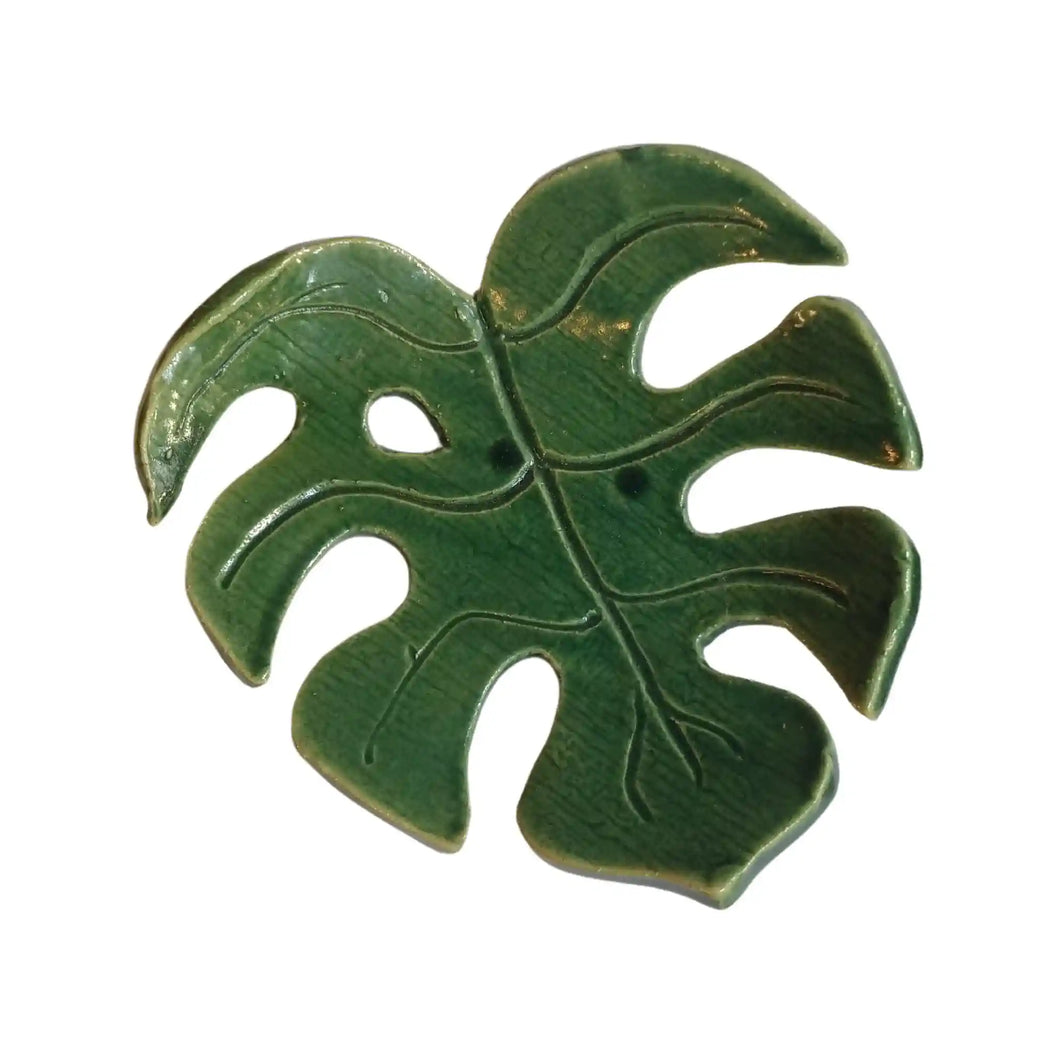 Decorative ceramic monstera leaf dish by Wellhandled Ceramics. Dark green with holes and leaf veins carved into the surface.