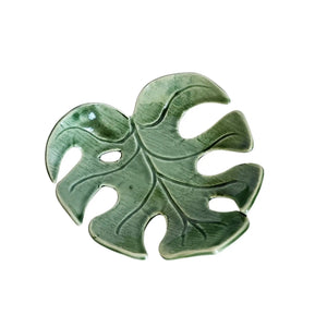 Decorative ceramic monstera leaf dish by Wellhandled Ceramics. Dark green with one leaf hole and distinctive leaf veins carved into the surface.