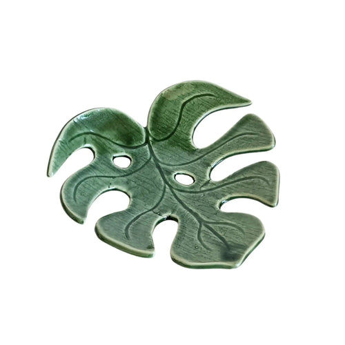 Decorative ceramic monstera leaf dish by Wellhandled Ceramics. Dark green with two leaf holes and distinctive leaf veins carved into the surface.
