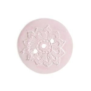 Baby pink circular ceramic soap dish handmade by Wellhandled Ceramics with 3 drainage holes and embossed with lace.