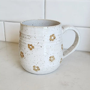Ceramic coffee mug with handle handmade by Wellhandled Ceramics. White speckled glaze with daisies embossed into the glaze.