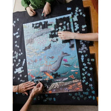 Whale Poo and CO₂ jigsaw puzzle in action! Scene featuring a family making the jigsaw which is mostly complete and three pairs of arms are working on the jigsaw.