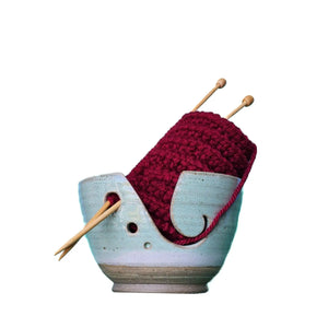 Ceramic yarn / wool bowl to hold your knitting or crochet project and keep it safe. A hand carved koru swirling shape on the side. Hand thrown in Christchurch and glazed with a silky light green slightly speckled glaze. Seen here with deep red yarn and bamboo knitting needles.
