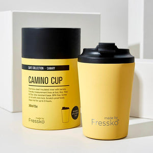 Insulated Made by Fressko stainless steel 12oz reusable camino coffee cup in a bright canary yellow colour with packaging in the background.
