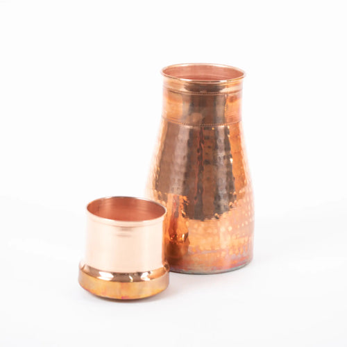 A beautiful avocado shaped hammered copper water flask with a large lid that sits inside the top of the bottle which can be used as a cup to drink out of.  In this image the cup / lid is sitting next to the flask, ready to be used.
