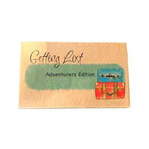 Adventurer's / Standard edition of the Getting Lost Adventure game in a kraft cardboard box with blue cloud and a stack of two vintage suitcases on the front.