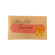Summer edition of the Getting Lost Adventure game in a kraft cardboard box with a pink cloud and a pair of jandals on the front.