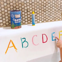 Honeysticks bath crayons seen here in action writing the alphabet on the side of a bath tub. Reusable metal tin containing 7 natural beeswax crayons.