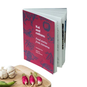 Kai and culture: Food stories from Aotearoa book standing open in front of a wooden chopping board with garlic, beans and radishes. New Zeland book about food culture by Freerange Press.