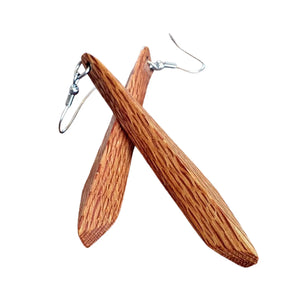 Two wooden hook earrings made from recycled Rewarewa wood by Liberation Jewellery. One earring is laying on top of the other and the beautiful, patterned grain is evident.