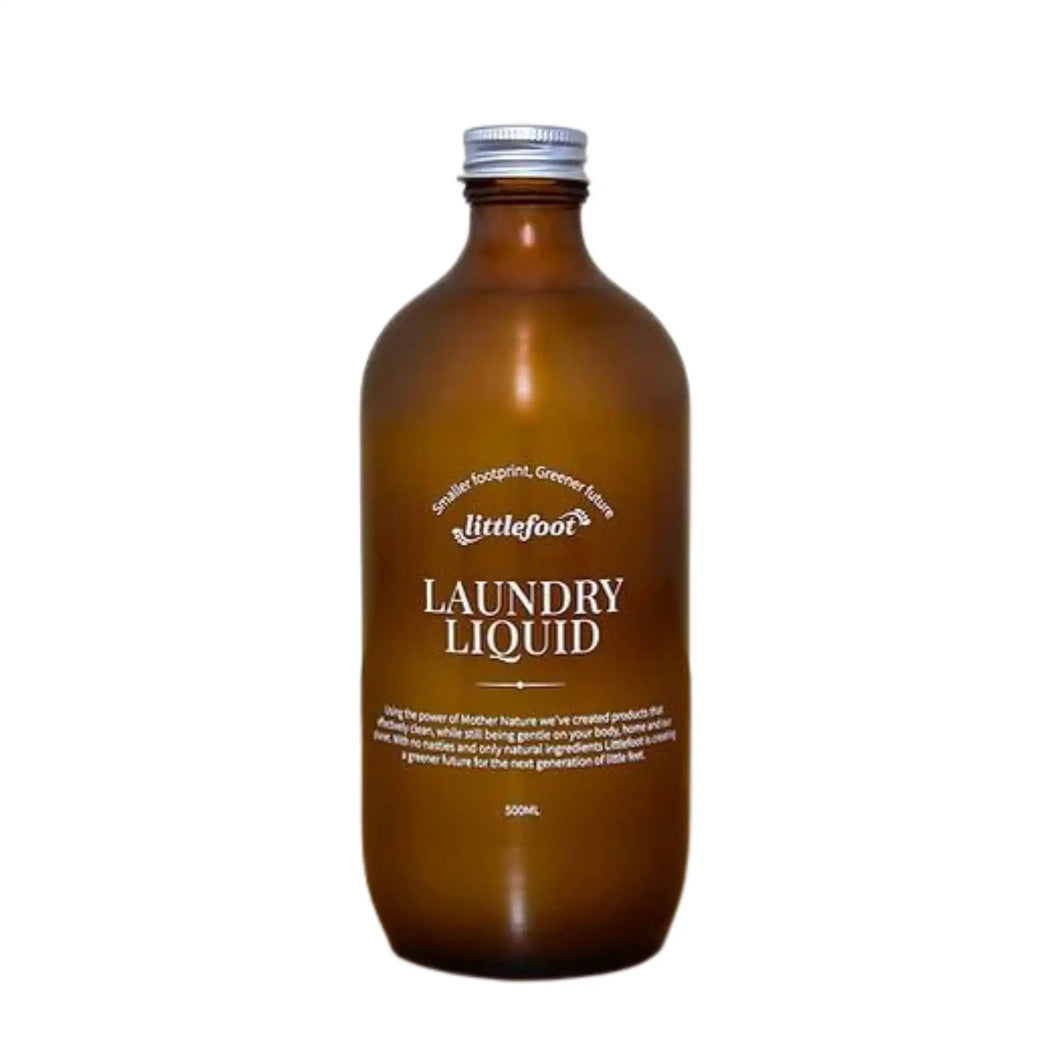 500ml amber glass bottle with aluminium screw-top lid containing laundry liquid. The clear label with white text reads: smaller footprint, greener future, Littlefoot logo, and Laundry Liquid.