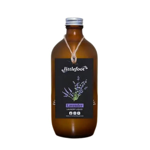500ml amber glass bottle with aluminium screw-top lid containing laundry liquid. The label is obscured by a black swing tag which is attached to the neck of the bottle with jute twine. The swing tag has an illustration of flowering lavender springs and the Littlefoot logo, it reads Lavender Laundry Liquid.