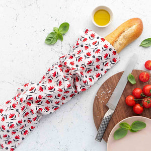Organic reusable bread bag in pohutukawa design with French bread and tomatoes.