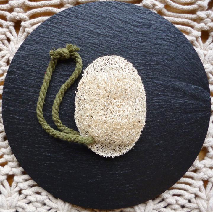 New Zealand grown Loofah body sponge with a soft cotton handle on a black background.
