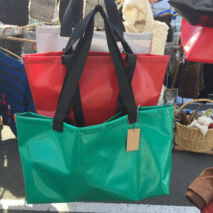 Display of three totes in green, red and grey.