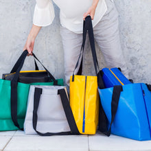Person holding a selection of totes in various colours.