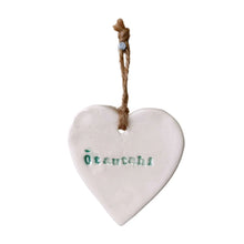 A beautiful white ceramic hanging heart embossed with the letters "Ōtautahi" which means Christchurch in te reo Māori, the letters are a beautiful deep green and there is a jute sting attached to the top of the heart to hang it up with.