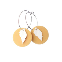 Eco friendly Beachcomber earrings made from recycled ice-cream container lids in Ōtautahi Christchurch by Remix Plastic. Hypoallergenic hoops which are silver in colour and a sand coloured disk with a white shell in front.