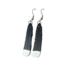 The new design of Remix Plastic's Huia feather earrings, made from recycled 3D printer waste. Black feathers with painted white tips.