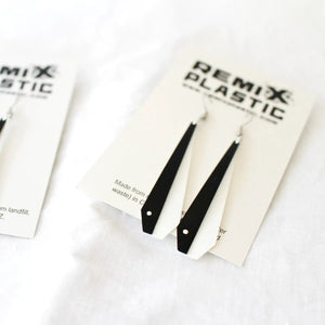 Eco friendly Pīwakawaka or Fantail Feather earrings made from recycled ice-cream container lids in Ōtautahi Christchurch by Remix Plastic. Hypoallergenic hooks which are silver in colour and a feather which is black on one half and white on the other, the two halves are pinned together with a handmade silver pin. Seen here with the minimalist packaging which is a simple card with the Remix Plastic logo and the earrings attached.