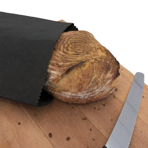 SammyBags reusable paper bag on a bread board with a loaf of bread inside and a bread knife alongside.