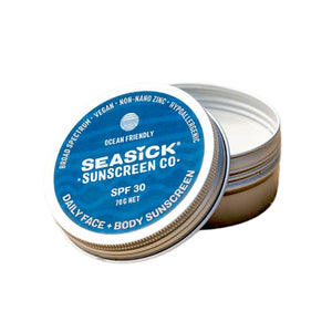 Aluminium tin of Seasick Sunscreen Co. sunscreen with the lid off. The label on the front is deep blue with white writing and reads: Ocean Friendly, SPF30, Daily face & body Sunscreen, Broad Spectrum, Vegan, Non-nano zinc and hypoallergenic.