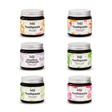 All six flavours of Solid Oral Care toothpaste in six amber glass jars with colourful labels. Flavours include, fresh mint, fresh mint - sensitive, cinnamon, orange, spearmint and strawberry.