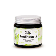 Solid Oral Care spearmint toothpaste with fluoride in an amber glass jar and aluminium lid. The white label with light green swirls reads made in NZ and plastic free.
