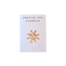 Sustainable greeting card which reads "Sending you sunshine" with a sun emitting rays underneath which is made from fabric and has been stitched onto the greeting card. Created from second-hand fabric which has been lovingly eco-dyed in Ōtautahi Christchurch by The Clothworks using local flora from our Garden City.
