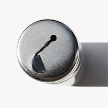 Close up top view of a reusable stainless steel dental floss container with a side shadow on a white background. 