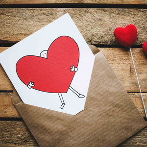 Brown paper envelope with drawing of person holding large red heart on a white card.